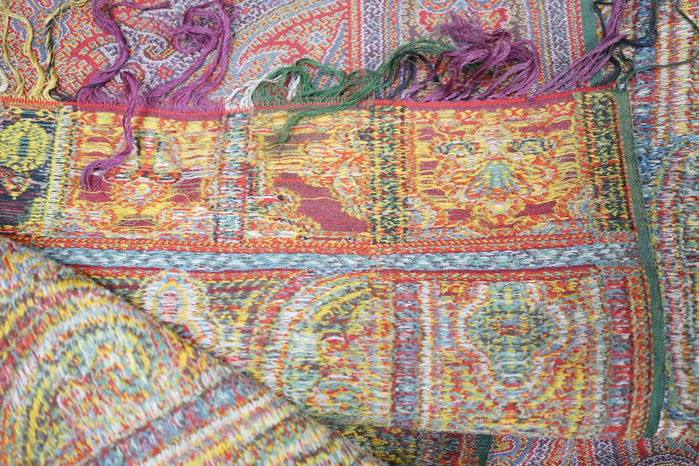 A 19th century woven multi coloured wool and silk Paisley shawl, with large all over paisley tear drop design and brightly coloured fringed borders, 335cm long x 166cm wide